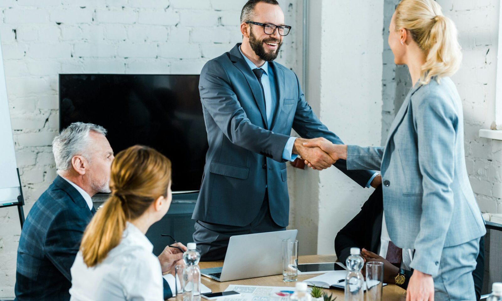 beau-coach-d-affaires-serrant-la-main-d-une-femme-blonde-auprès-de-collaborateurs-multiculturels
