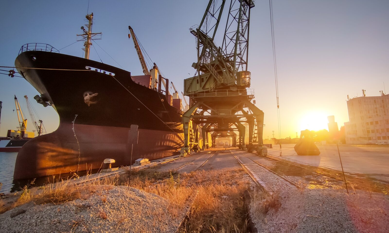 cargo ship bulk carrier is loaded with grain of wheat in port at sunset