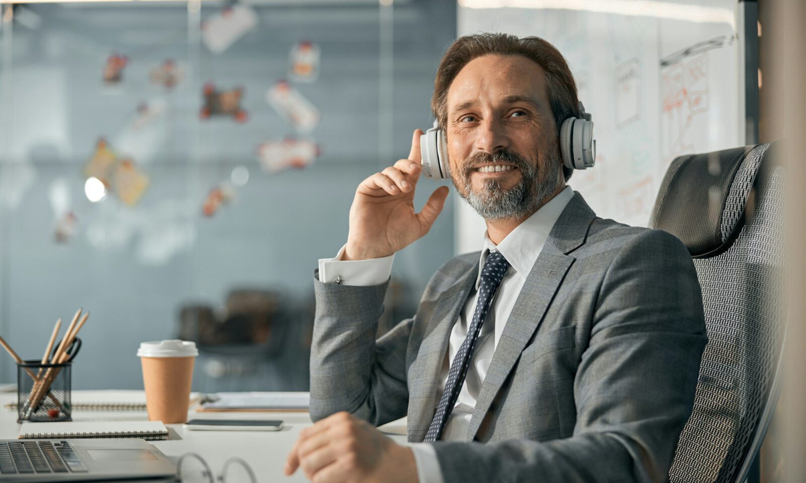 homme-d'affaires-heureux-avec-casque-sans-fil-écoutant-un-webinaire-pédagogique