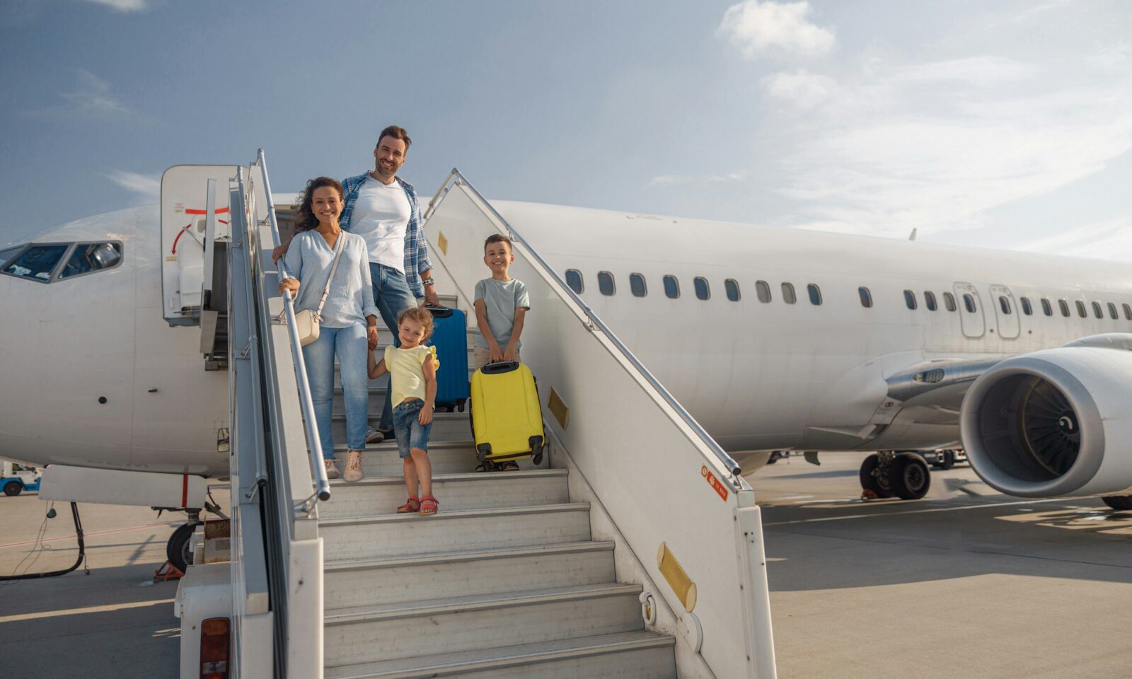 famille-heureuse-de-quatre-personnes-descendant-de-l-avion-en-plein-jour