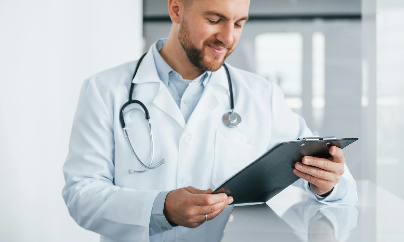 segurando-bloco-de-notas-médico-profissional-de-jaleco-branco-está-na-clínica
