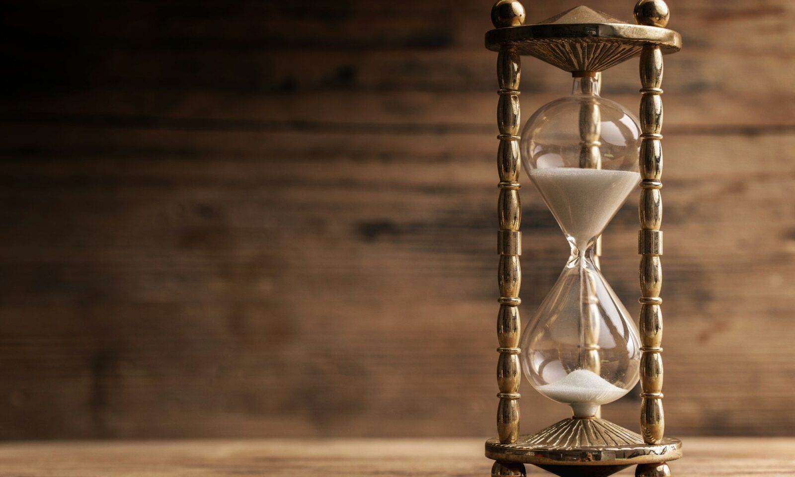 hourglass-on-the-wooden-table-with-a-wooden-background