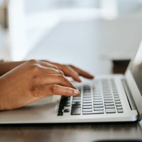 Laptop, hands typing and writer with research for website copywriting, newsletter and blog ideas or
