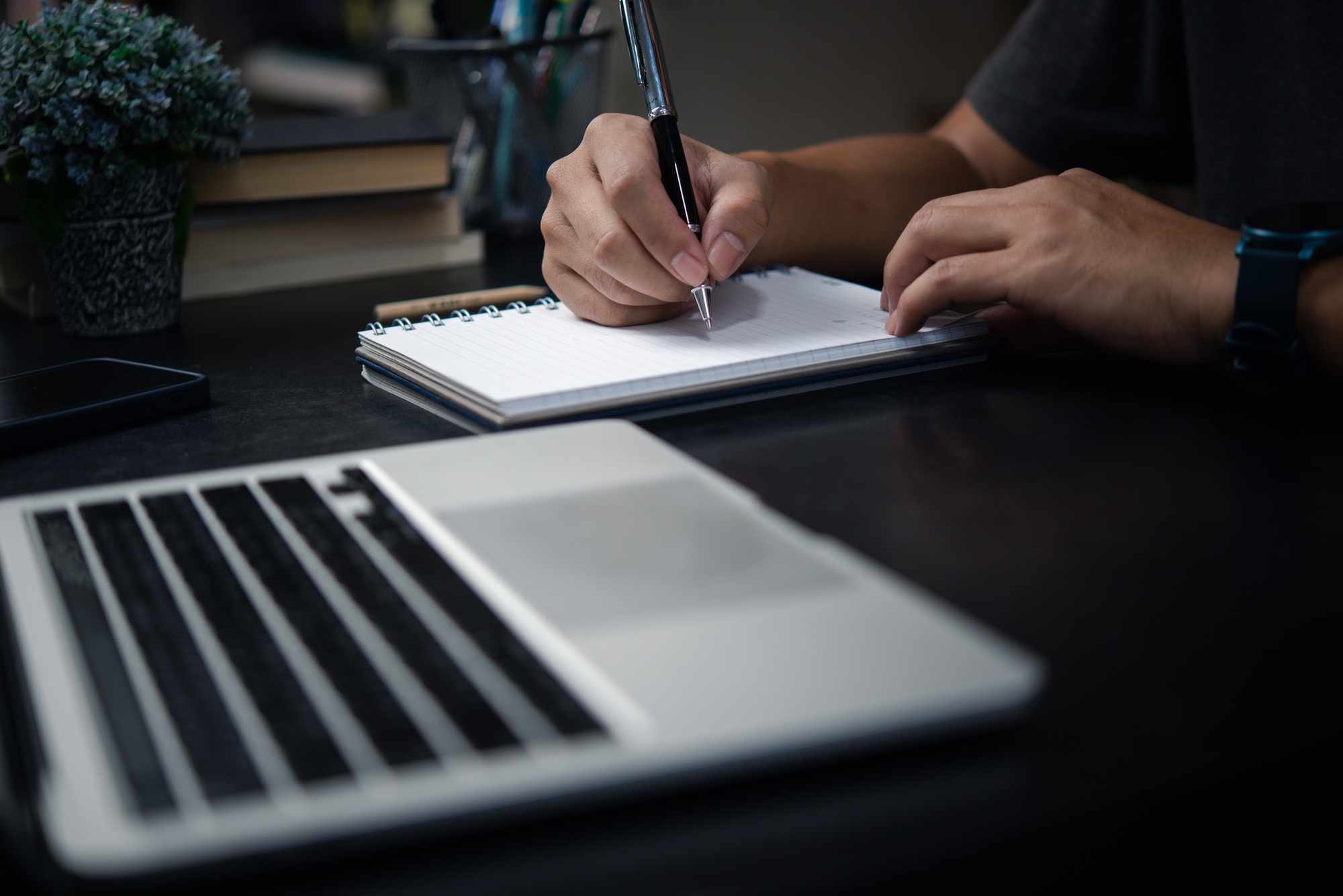 Mão de homem escrevendo em caderno com laptop. Planejamento de negócios, aprendizagem eletrônica, conceito de diário.