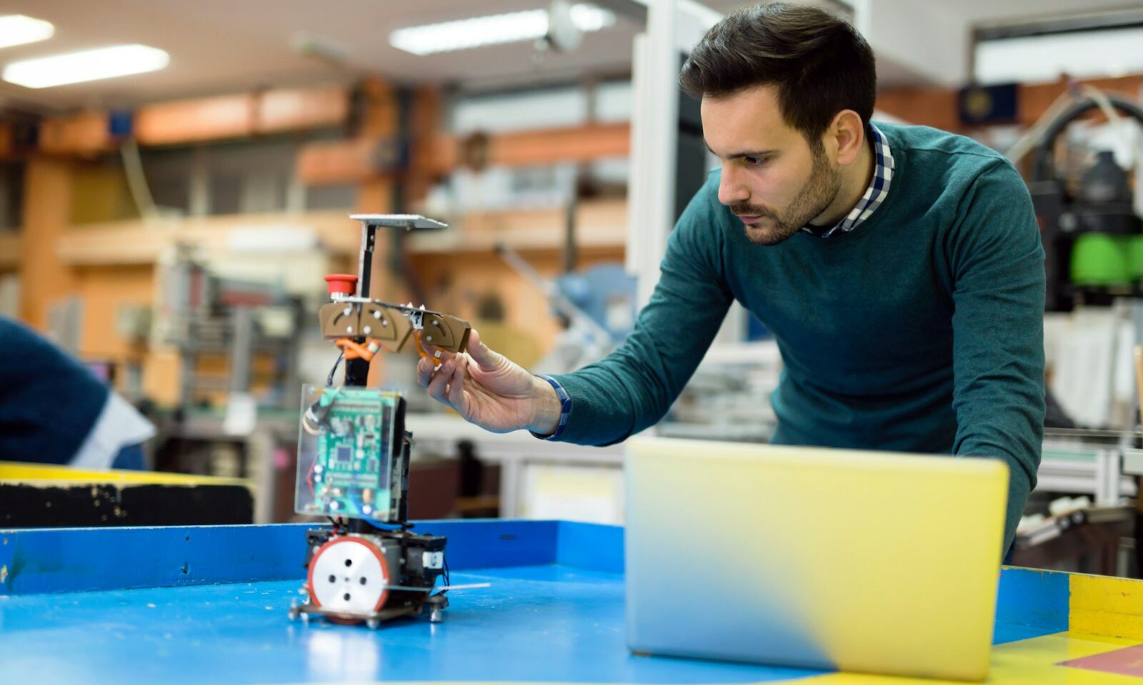 jeune-ingénieur-testant-son-robot-dans-l-atelier